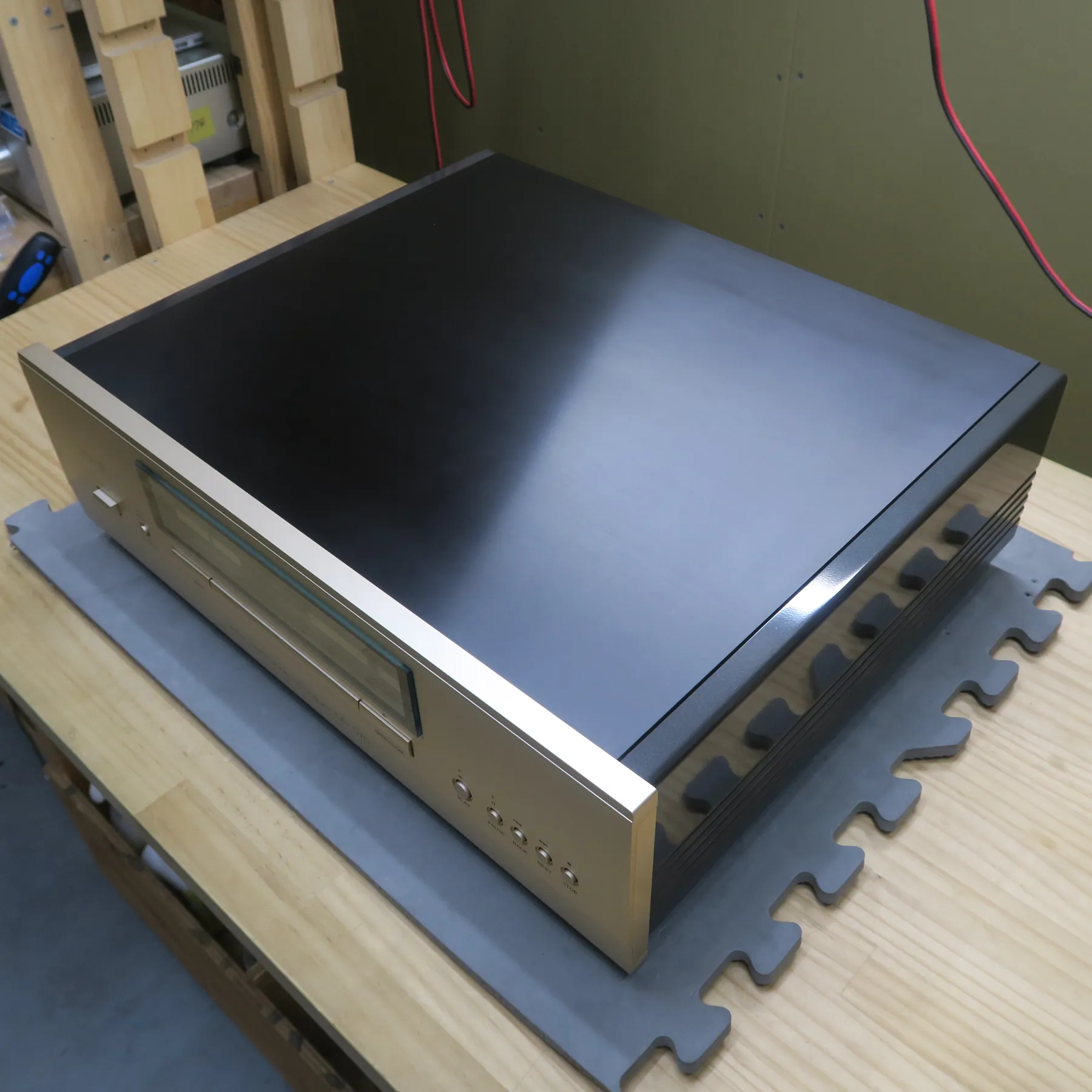 アキュフェーズ DP-570 CDデッキの斜め前から見た外観、直方体、前面パネルはシャンパンゴールドのヘアライン仕上げ金属、ディスプレイ窓、トレイ開口部、再生、一時停止、戻る、次へ、天板は黒色マット仕上げ金属、右側板は黒色光沢仕上げで横溝がある