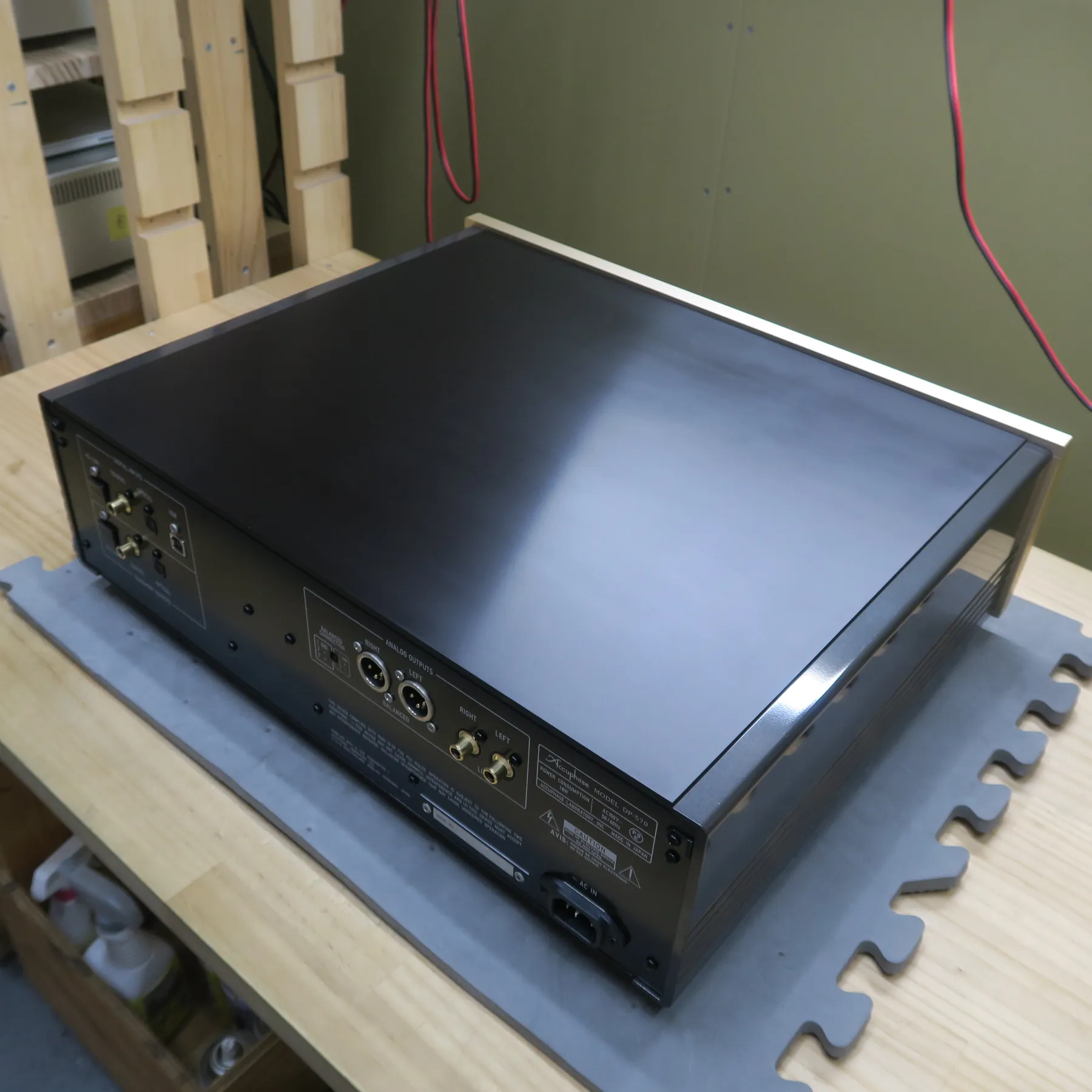 アキュフェーズ DP-570 CDデッキの斜め後ろから見た外観、黒色の筐体、天板と側面は光沢、上部縁はシャンパンゴールドのヘアライン仕上げ、背面はマットな黒色でアナログ出力