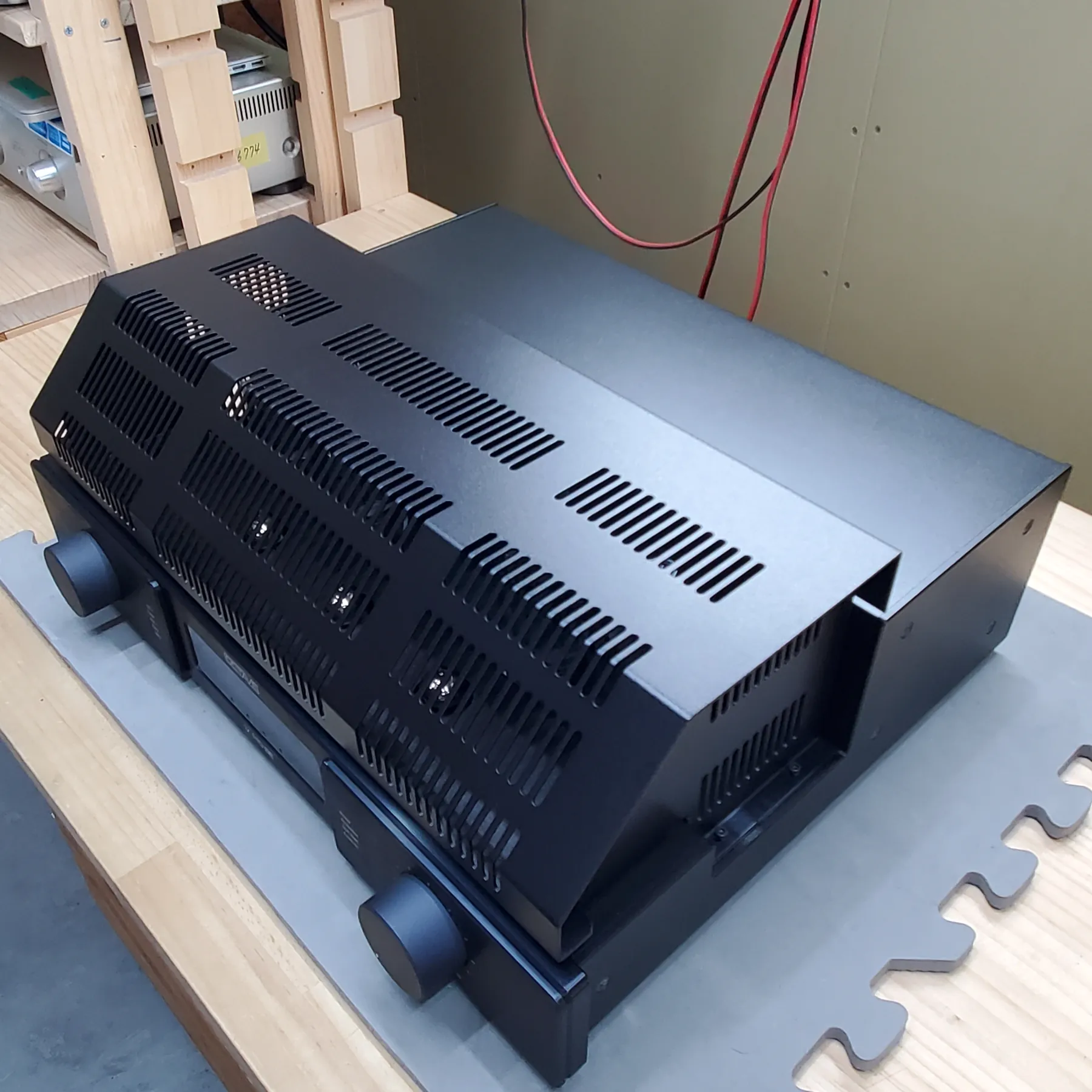 オクターブ V110SE LINE プリメインアンプの斜め前から見た外観、黒色金属筐体の機器が二段に積まれている、上段は前面傾斜部に多数の放熱スリット