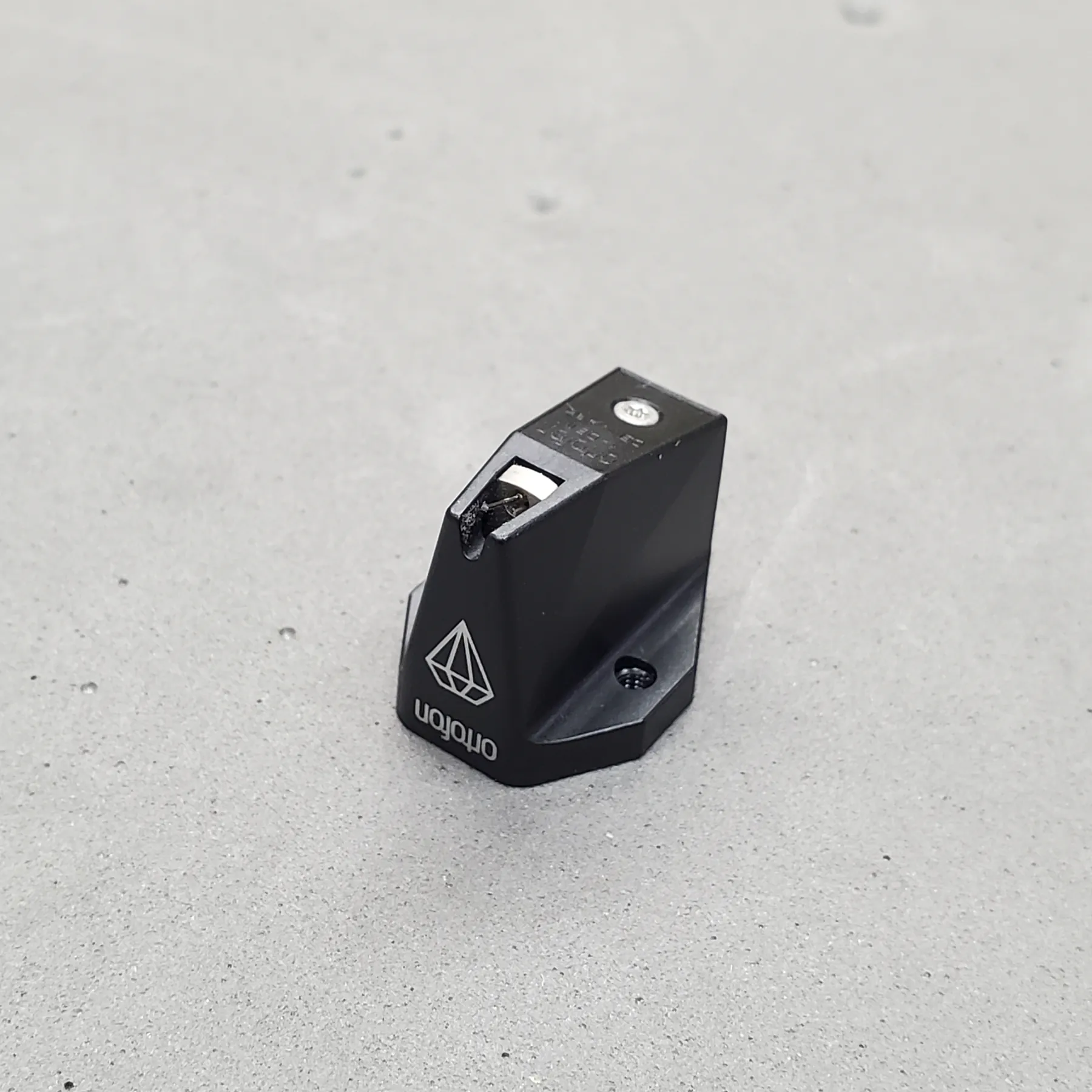 オルトフォン MC X40 MCカートリッジの斜め前から見た外観、黒色のマット仕上げ筐体、多角形の立体形状、前面は斜めカットの開口部、銀色の部品が見える、天面に銀色のネジ、底面に黒色のネジ穴