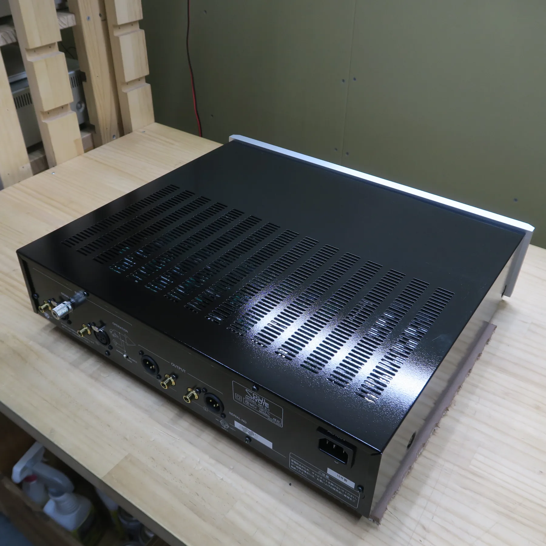 ソウルノート E-1 フォノイコライザーの斜め後ろから見た外観、黒色金属筐体、天板は光沢黒で多数の放熱スリット、側面は木目調パネル