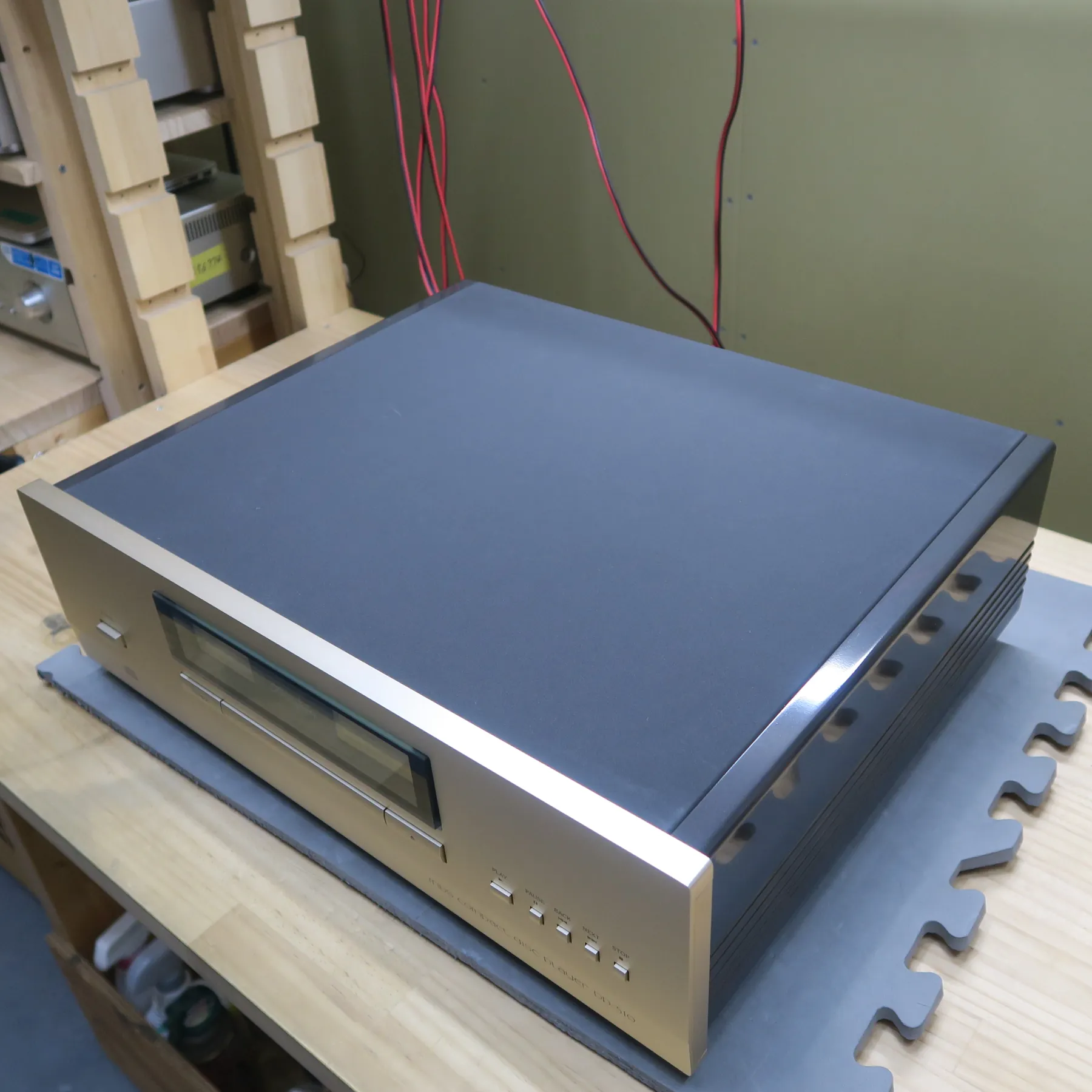 アキュフェーズ DP-510 CDデッキの斜め前から見た外観、前面パネルはシルバーヘアライン金属製で天板と側板を覆うL字型、天板はダークグレーマット仕上げ、右側板は光沢のあるダークグレーで横溝、前面にディスプレイ窓、トレイ開閉部