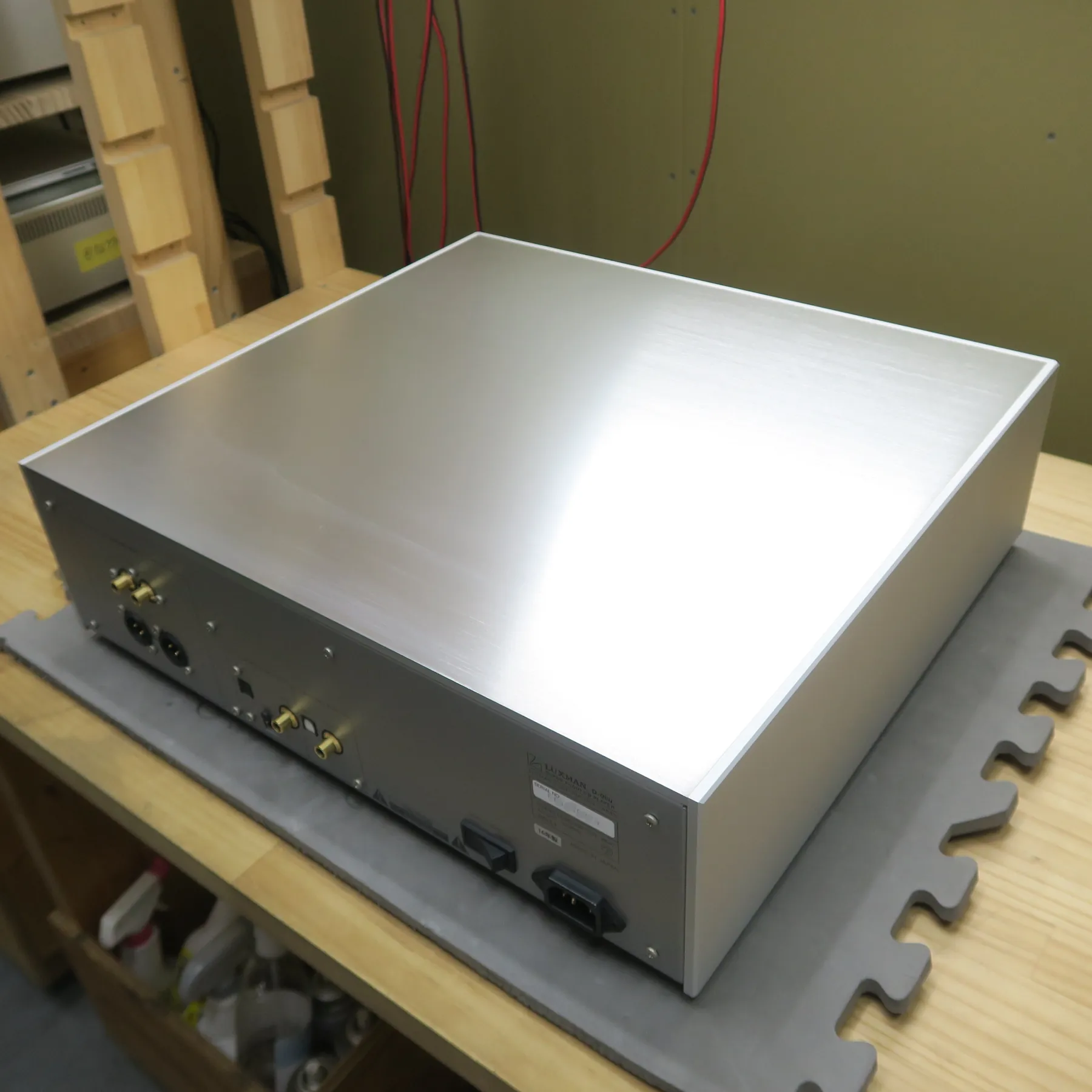 ラックスマン D-06u CDデッキの斜め後ろから見た外観、直方体の筐体、天板と右側面はシルバーのヘアライン仕上げで光沢がある、背面はグレーの金属製で各種入出力端子