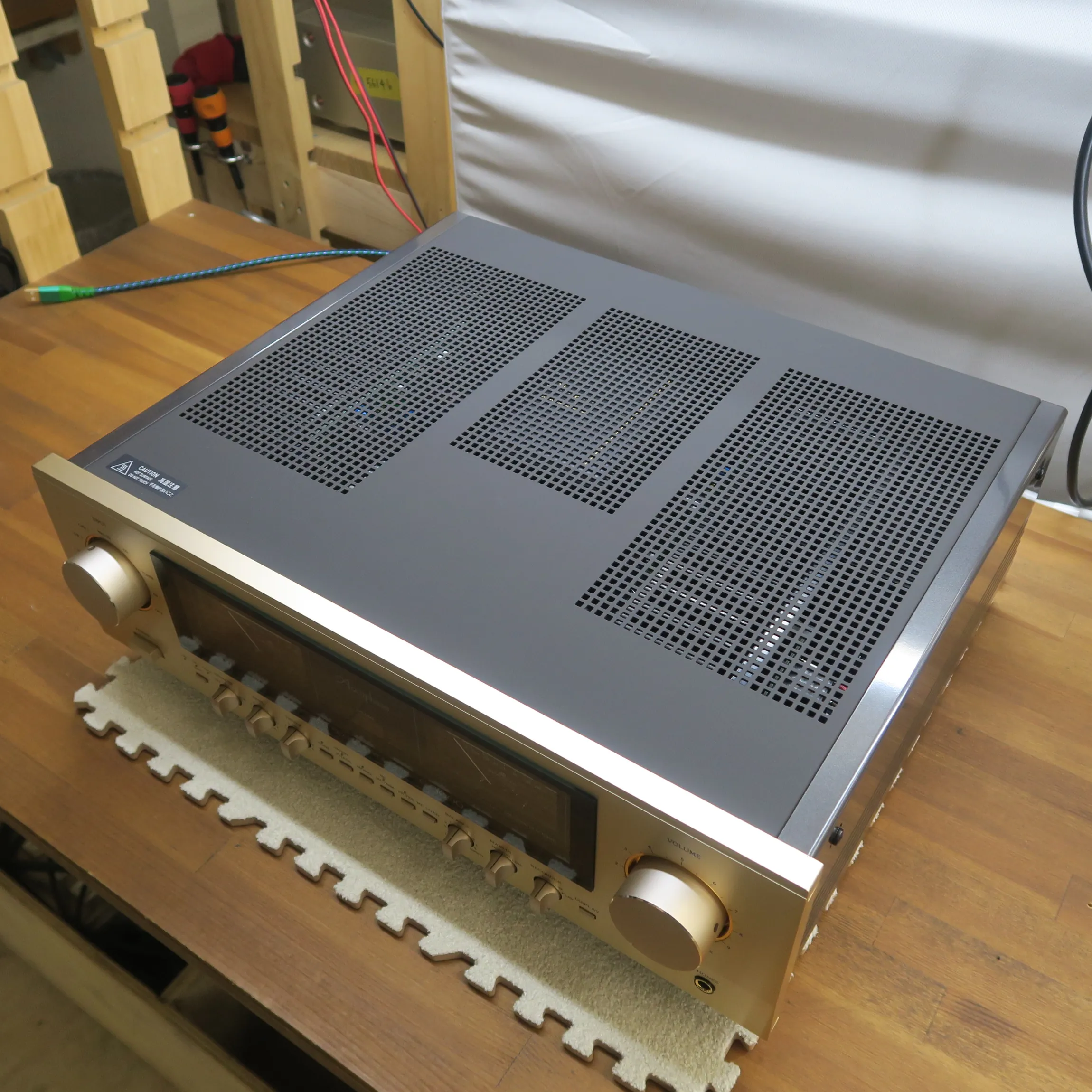 アキュフェーズ E-3000 プリメインアンプの斜め前から見た外観、前面パネルはシャンパンゴールドの金属製ヘアライン仕上げ、黒いディスプレイ窓、天板はダークグレーの金属製で通気孔、側板は光沢あるダークグレーの金属製