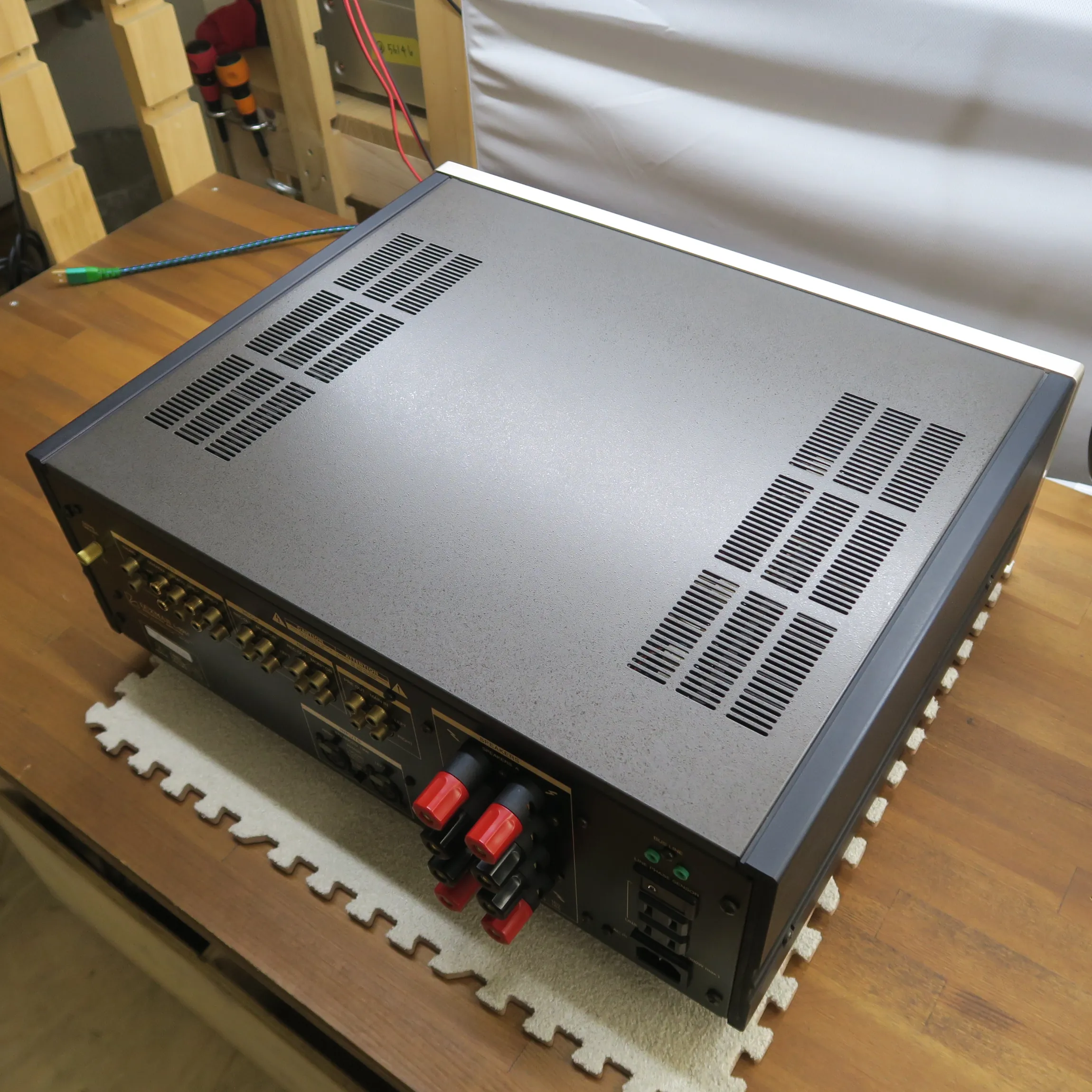 ラックスマン L-505f プリメインアンプの斜め後ろから見た外観、直方体の筐体、天板は濃いグレーの梨地仕上げで放熱孔、縁にクリーム色の帯状装飾、側面と背面は黒色 背面には金色の入力端子、その他接続端子