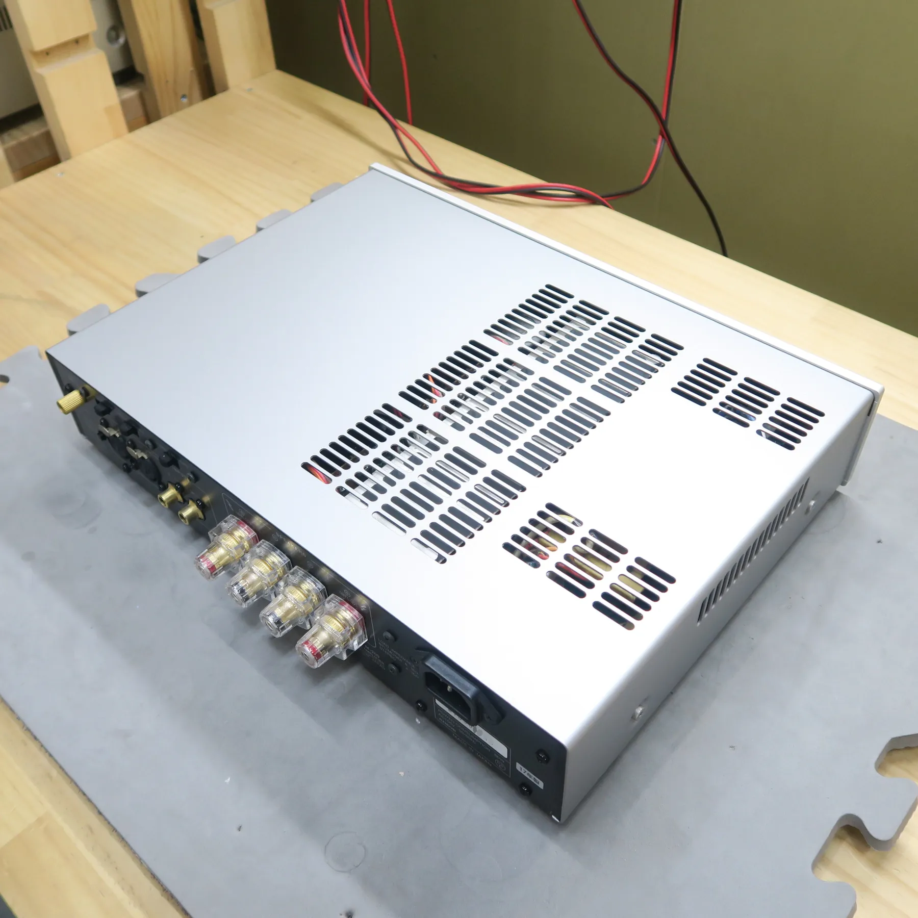 ラックスマン M-200 パワーアンプの斜め後ろから見た外観、銀色の金属製薄型筐体、天板と右側面はマットな銀色で多数の放熱スリット、背面は黒色で金色のRCA入力端子やスピーカー出力端子等